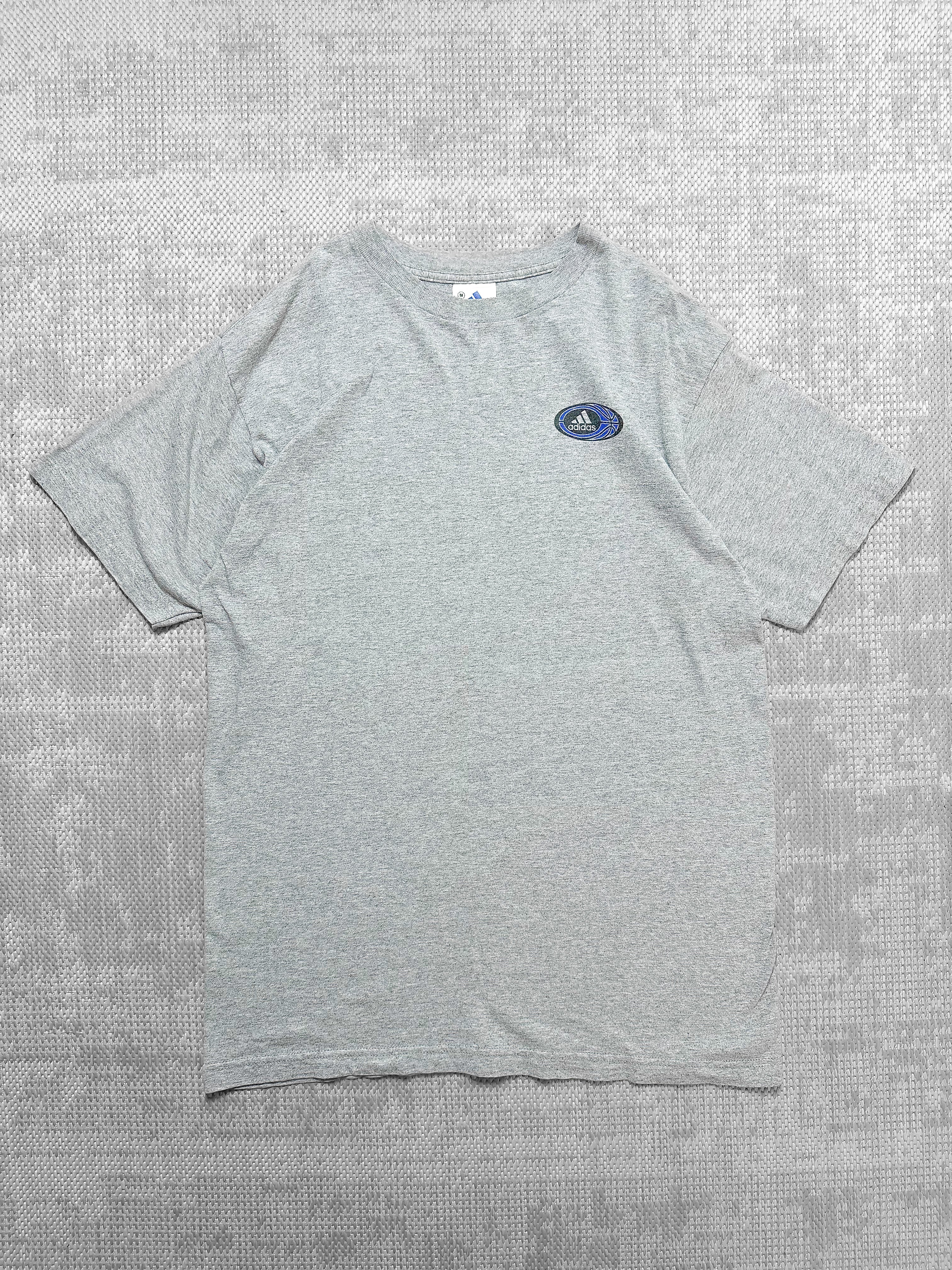 Adidas short-sleeve grey T-shirt with front logo badge featuring text, stripes, and a blue basketball graphic; back has bold basketball-themed design.